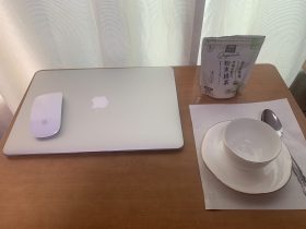 MacBook pushed aside with Japanese teacup and green tea pouch ready