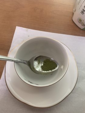 A small amount of green tea powder resting on the tip of a dinner spoon