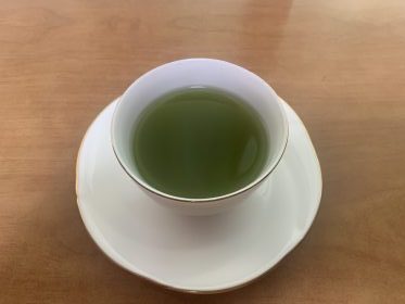 A cup of green tea served with a packaged Choco Pie snack