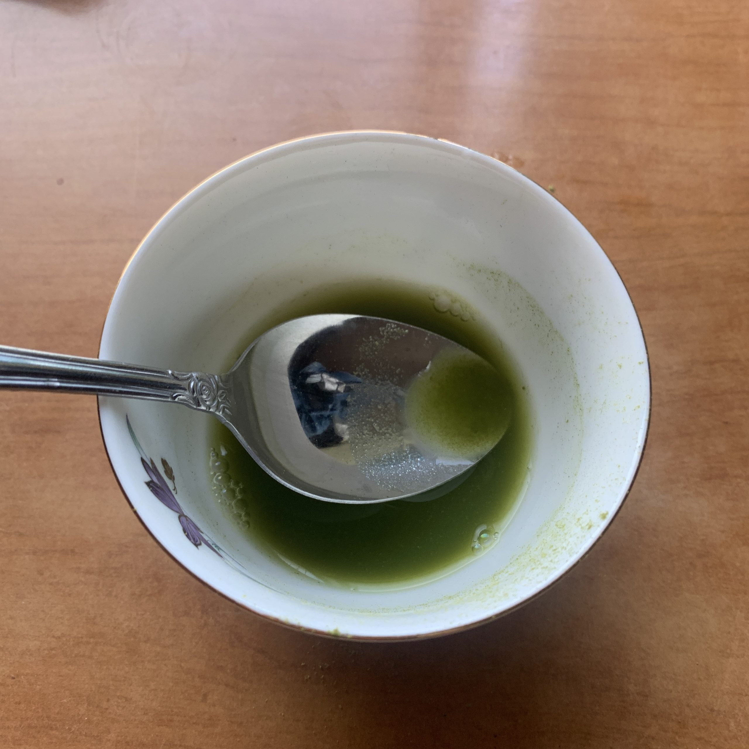 Gently smoothing matcha powder into a paste using the back of a spoon